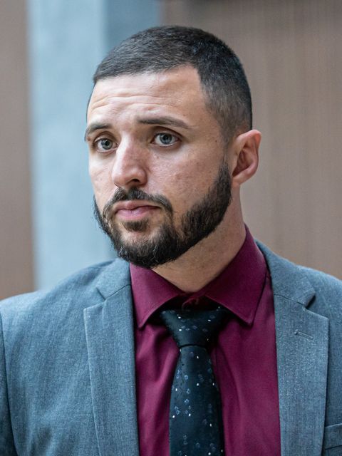 Dr. Nicolas Guimarães Novais Pinto Mendes, de terno cinza, camisa vinho e gravata escura, durante entrevista
